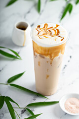 Caramel milk tea latte in a tall glass with cold foam and caramel sauce