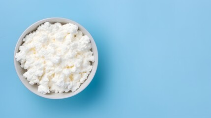 Cottage cheese in glass bowl isolated on blue background, top view