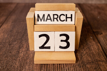 Cube shape calendar for March 23 on wooden surface with empty space for text.