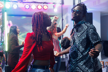 Relaxed african american man and woman dancers partying on nightclub dancefloor. Young boyfriend...