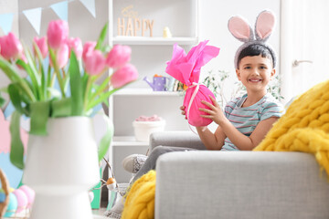 Cute little boy wearing bunny ears with Easter gift egg at home