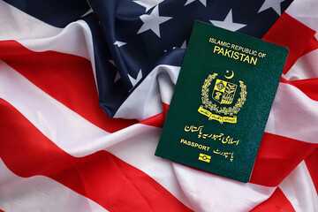 Green Islamic Republic of Pakistan passport on United States national flag background close up. Tourism and diplomacy concept