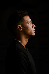 Low key portrait of young African man in serious profile looking up