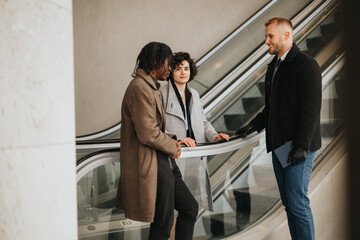 Three business people in winter attire engage in a friendly discussion while descending an escalator in a modern business setting.