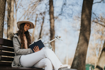 A fashionable young woman enjoys a book sitting on a park bench beside her bicycle, savoring a beautiful sunny day.