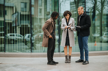 Three businesspeople engaging in a casual business discussion outside an office building.