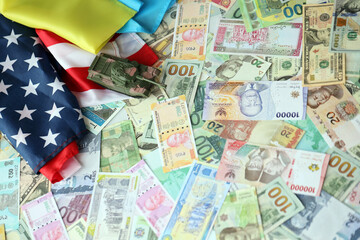 Toy tank on US flag and ukrainian flag on many banknotes of different currency. Background of war funding and military support between United States and Ukraine