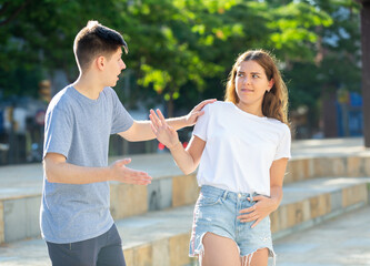 Young man is pestering teenage girl on the street