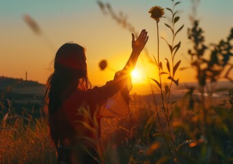 Obraz premium woman holds hand up to the sun at sunset, in the style of realistic depiction of light