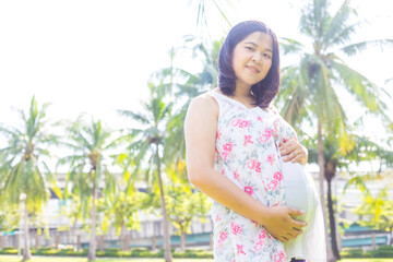 Asian young happy pregnant woman relaxing and enjoying life in nature park sunshine ligfht - 742064501