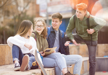 Four teenagers are talking about play on walk on the street