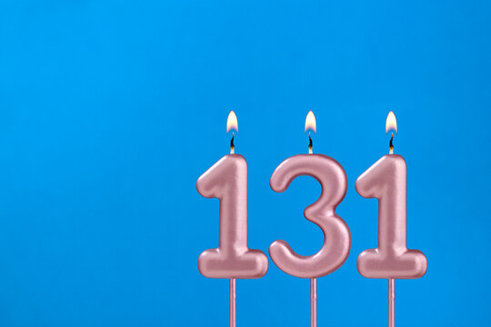 Number 131 - Burning anniversary candle on blue foamy background