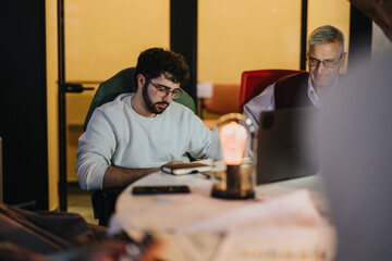 Multi generational coworkers analyze data, plan strategies, and discuss business growth in an evening meeting.