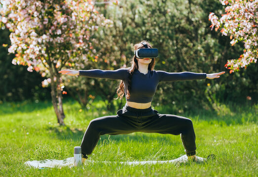 Woman with VR headset doing yoga in park, virtual reality fitness, immersive technology