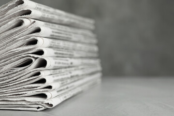 Stack of newspapers on light grey stone table, closeup with space for text. Journalist's work