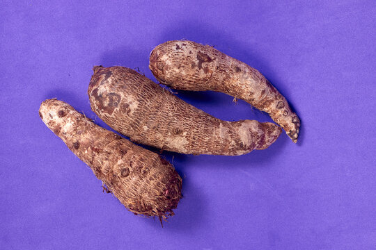 closeup of taro root vegetable, eddo malanga, purple background