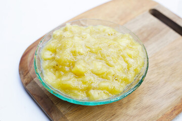 Mashed banana in bowl on white background.