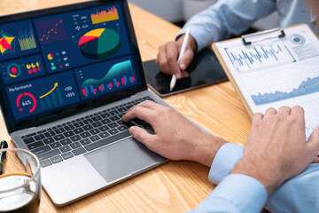 Financial data analysis dashboard by Fintech BI or business intelligence display on laptop screen to in-depth financial data analysis by business people working on business marketing. Meticulous