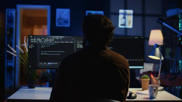 Man doing IT support job from home office, stretching after sitting on desk chair all day. Programmer loosening up, relaxing after typing on computer for long period of time, camera B