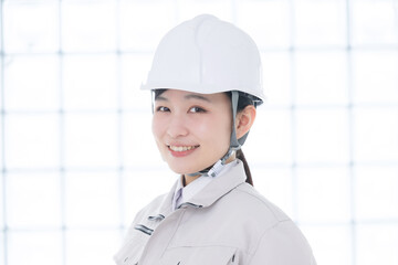 作業着を着たカメラ目線のヘルメットを被る女性のクローズアップ