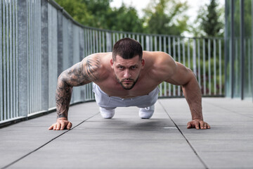 Fototapeta premium Sexy muscular man pumps his muscles and lifts dumbbells in gym. Strong fit man exercising with dumbbells. Muscular young handsome man lifting weights. Weightlifting and training with dumbbells.