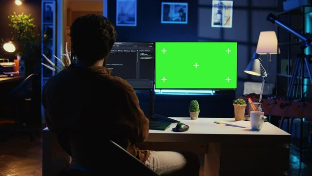 Self employed man doing IT support job from apartment personal office, coding on green screen PC. Software developer writing lines of code on mockup computer at home, camera B