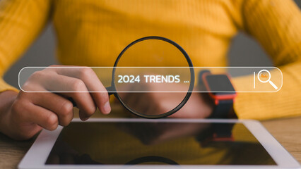 Women holding magnifier glasses with the text New Year 2024 Trends, emphasizing the main trend of...
