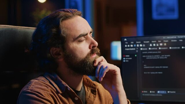 Software technician puzzled in front of computer screen while writing complex code, thinking of solution. IT expert feeling confused while trying to solve database bugs, camera A close up