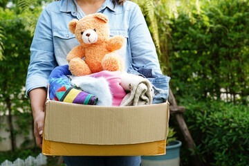 Volunteer collect cloth and doll in cardboard box to donate.