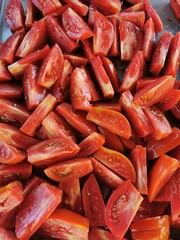 A colorful mound of perfectly cut tomato slices enticingly arranged on a smooth table surface.