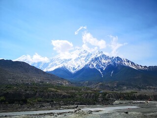 majestic snowy mountains looms in the distance, while a serene river flows gracefully in the foreground.