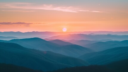 The first light of sunrise bathes a mountain range in warm hues, highlighting the textured layers and contours of the landscape.