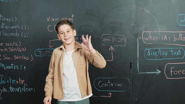 Back view of smart boy writing engineering prompt on blackboard. Attractive happy student planing a project by using coding and programing system in STEM technology classroom. Closeup. Erudition.