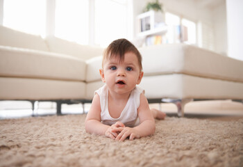 Fototapeta premium Portrait, growth and baby crawling on floor of living room in home for child development or progress. Adorable, curious and innocent with cute infant kid on carpet in apartment to learn motor skills