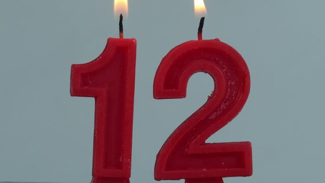 close up on a red number twelve birthday candle on a white background.
