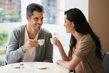 Love, conversation and couple with coffee on date for romance or anniversary in cafeteria. Happy,...