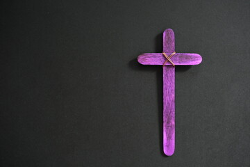 A purple wooden cross in black background. Christian faith, holy week or lent season celebration concept. - Powered by Adobe