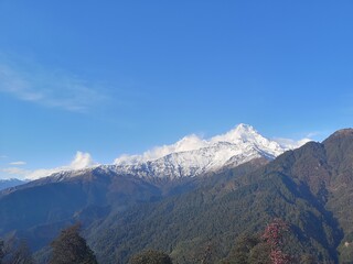 A majestic panorama of rugged snowy peaks stretching towards the sky, their silhouettes painted with hues of blue and purple.