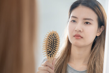 Asian woman very sad and upset looking at damaged hair, hair loss, hair thinning problem, vitamin...