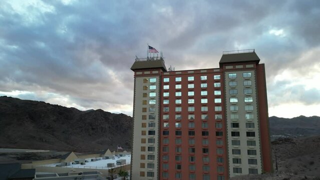 Aerial revealing rugged Nevada desert by Lake Mead past American flag on casino roof