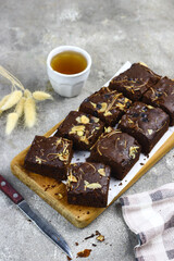 Brownies slices on chopping board, topping with almond and cheddar cheese grated. Tea time concept with grey background. Copy space for text. 