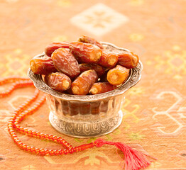 Vintage bowl filled with sacred Arabian dates, placed along with Islamic prayer beads. Holy month of Ramadan has significance with date fruit.