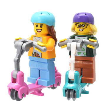 Lego minifigures of girls on electro scooter or motorbike. Editorial illustrative image of popular plastic toys.