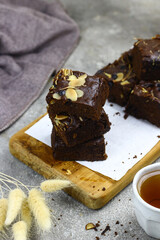 Brownies slices on chopping board, topping with almond and cheddar cheese grated. Tea time concept with grey background. Copy space for text. 