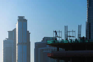 Obraz premium Skyscraper construction. Building under construction with workers at sunrise.