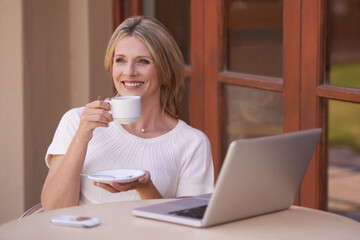 Happy, mature woman and thinking with coffee or laptop on table for morning, remote work or drink at home. Female person or freelancer smile with beverage or cup of tea by computer for networking