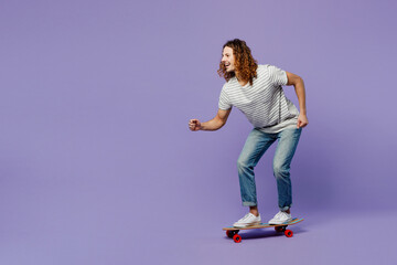Young side view cheerful man he wears grey striped t-shirt casual clothes riding skateboard...