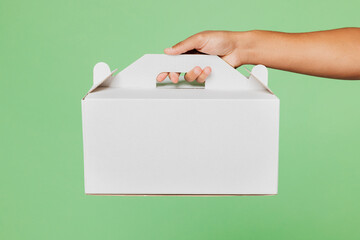 Close up cropped delivery guy male employee courier hold in hand cake dessert in blank cardboard...