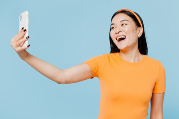 Young woman of Asian ethnicity wear orange t-shirt casual clothes doing selfie shot on mobile cell...