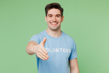 Young man he wear blue t-shirt white title volunteer stretch hand to camera for handshake gesture...